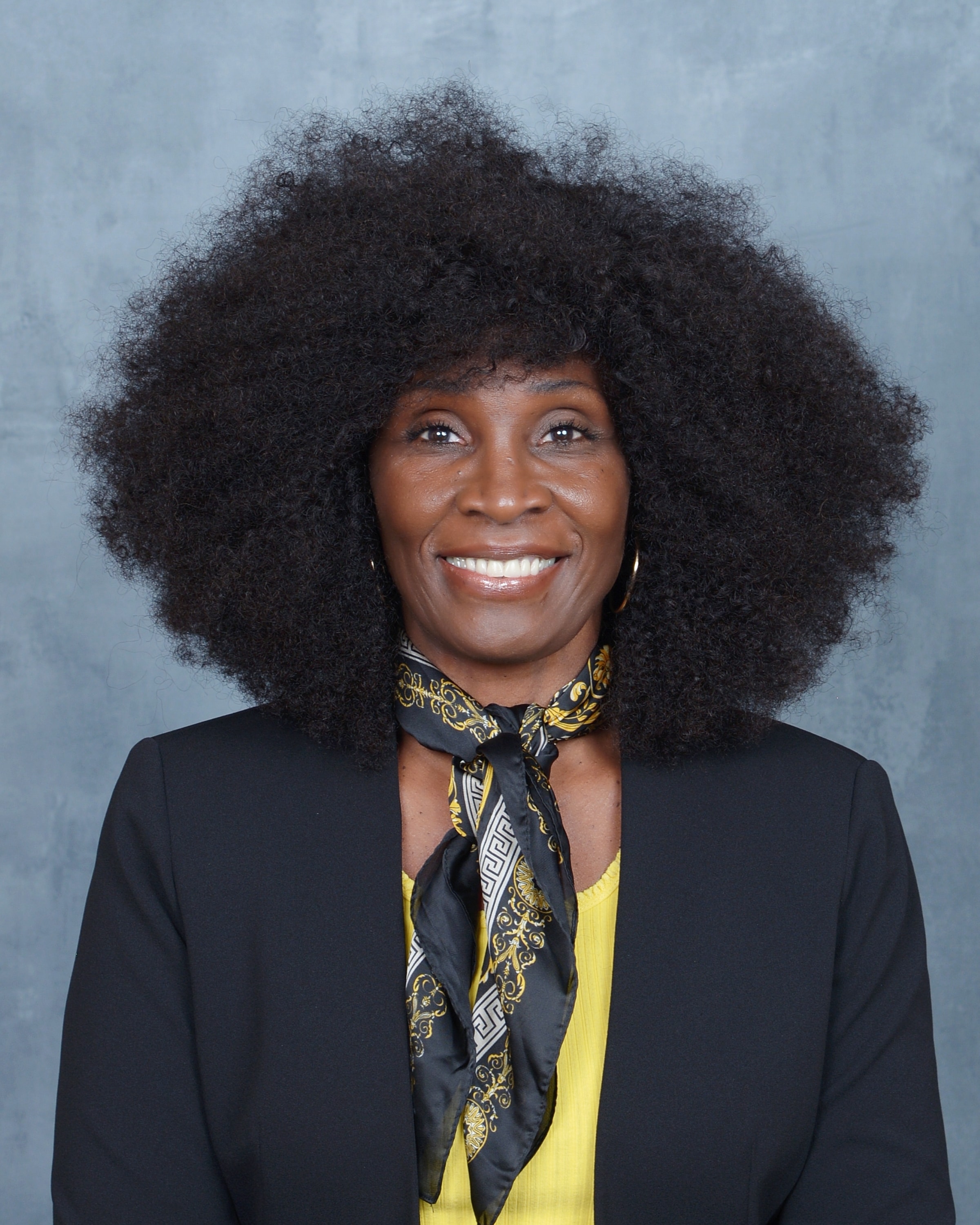 Portrait of Chaplain Dorcus Cater, Board Certified Chaplain, smiling warmly in a black blazer and patterned scarf